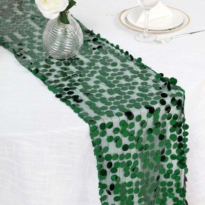 Green sequin table runner on a white table setting with decor.