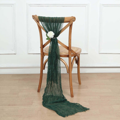 Green scarf draped over a wooden chair with a white flower accent.