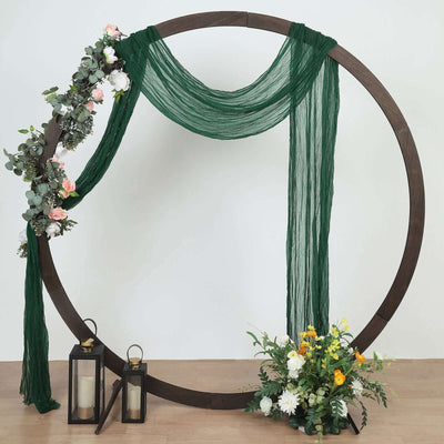 Decorative wedding arch with greenery and flowers on a plain backdrop.