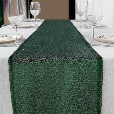 Green sequin table runner on a white table setting with glassware.