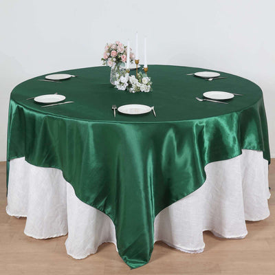 Round green tablecloth on a dining table set with plates and floral centerpiece.