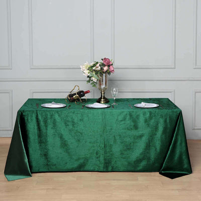 Elegant green tablecloth set for dining with wine and floral arrangement.
