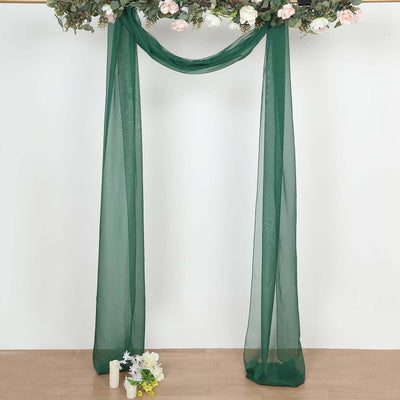 Green sheer fabric draped in a floral archway setup for events or photography.