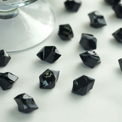 Black decorative crystals scattered on a white surface.
