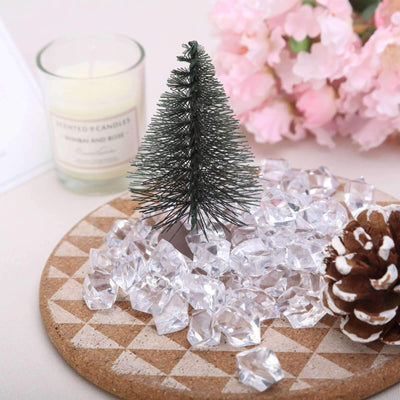 Miniature Christmas tree with faux crystals and pine cone on a decorative plate.