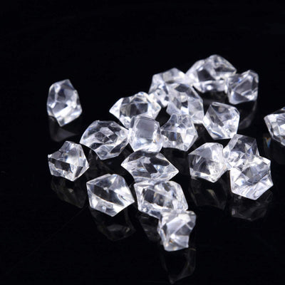 Scattered clear diamond-shaped acrylic gems on a black background.
