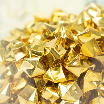 Shiny gold pyramid-shaped embellishments in a close-up shot.