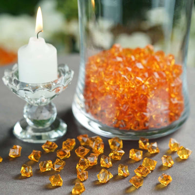 Orange decorative crystals with a candle in a glass holder.