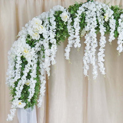 Artificial white floral arch with cascading blooms and greenery.