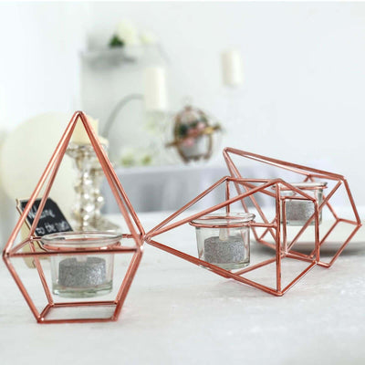 Geometric copper candle holders with glass containers and silver glitter accents.