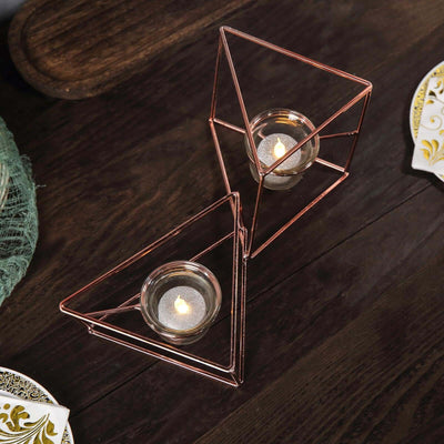 Geometric rose gold candle holders on a wooden table.