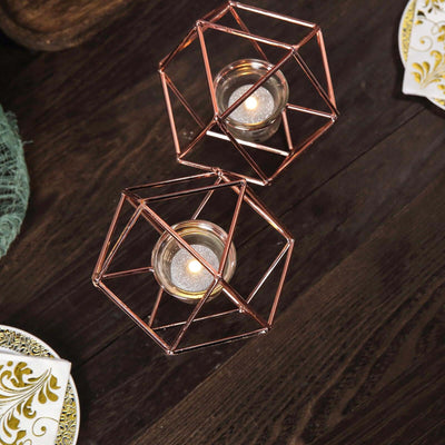 Geometric rose gold candle holders on a wooden table.