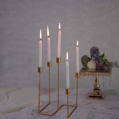 Elegant gold candle holder with white candles, lit and arranged stylishly.