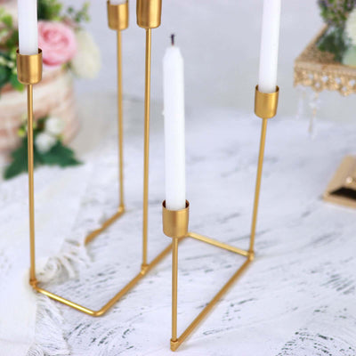 Elegant gold candle holder with white candles on a textured surface.