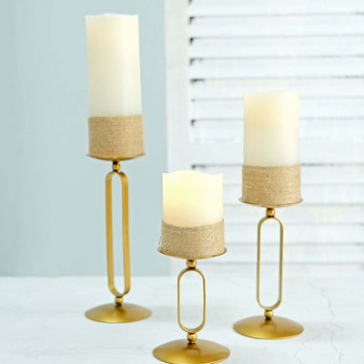 Gold candle holders with cream candles and jute accents on a light background.