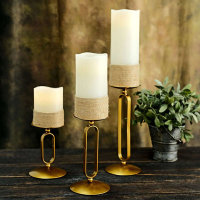 Elegant candle holders with textured accents and greenery backdrop.