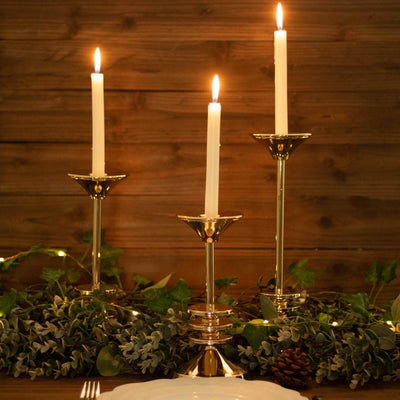 Elegant gold candle holders with white candles and greenery decor.