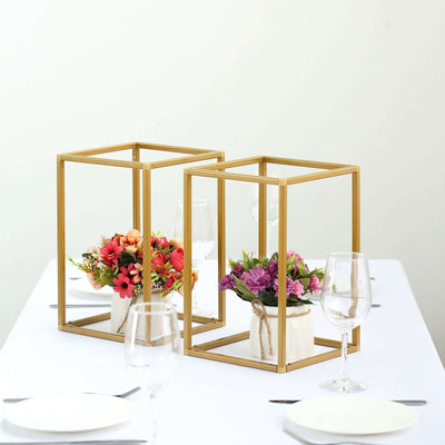 Gold geometric flower vases with colorful blooms on a dining table.
