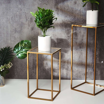 Stylish gold plant stands with potted greenery on a textured background.