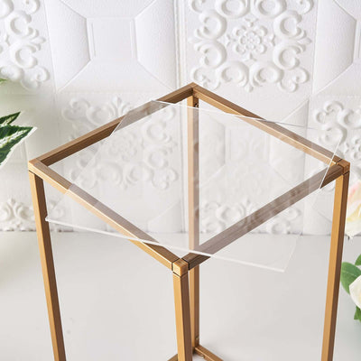 Clear acrylic table top on a gold metal frame against a textured background.