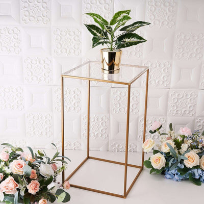 Modern gold plant stand with clear top and potted plant, styled with flowers.