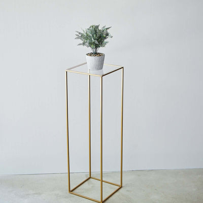 Gold metal plant stand with potted greenery on top