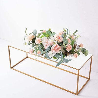 Table with pink roses and greenery on a clear glass top.