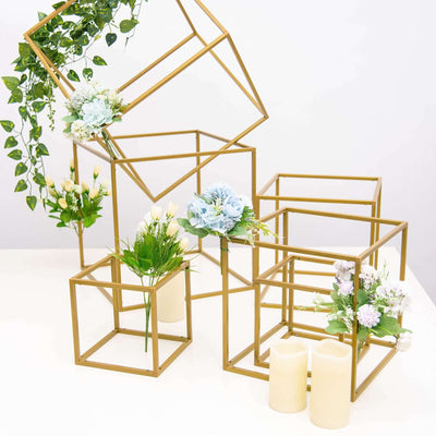 Gold geometric display stands with floral arrangements and candles.