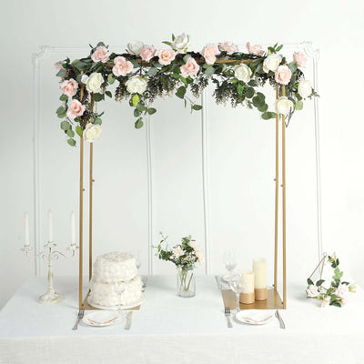 Floral wedding arch with roses and greenery over a decorated dining table setup.