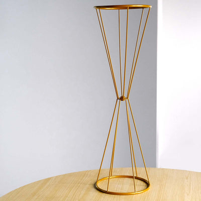 Gold wire plant stand on a wooden table against a light background.