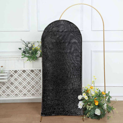 Black arch mirror with gold frame and floral arrangement in studio setting.