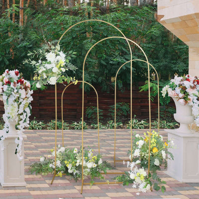 Elegant gold floral arch with white and green arrangements in a garden setting.