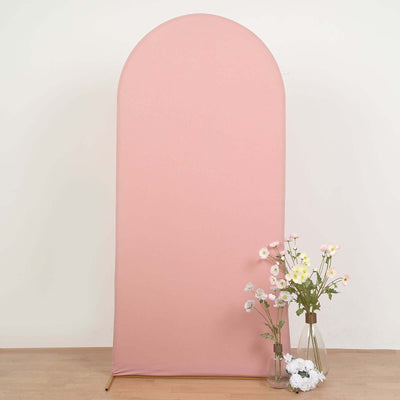Pink fabric backdrop with arched top and floral arrangements in vases.