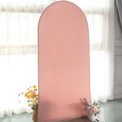 Pink backdrop with an arch shape and floral arrangements at the base.