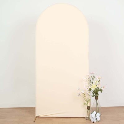 Beige arch backdrop with flowers in vases on a wooden floor.