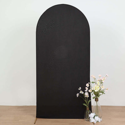 Black arched backdrop with flowers in vases on a wooden floor.