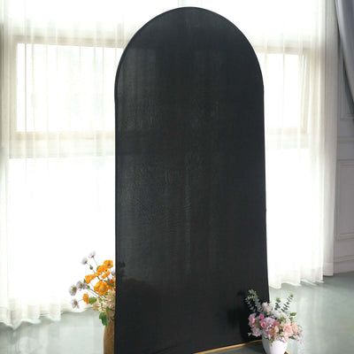 Black arched backdrop standing in a bright, airy room with flowers at the base.