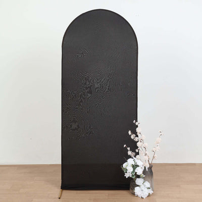 Black fabric backdrop with white floral arrangement in a vase.