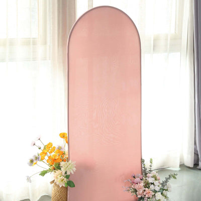 Pink backdrop with arch shape surrounded by flowers in a bright setting.