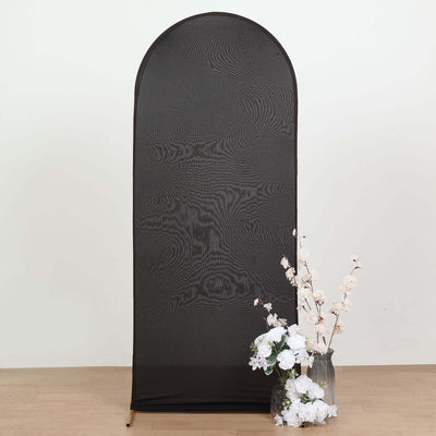 Black fabric backdrop with arched top and floral arrangement in vase.