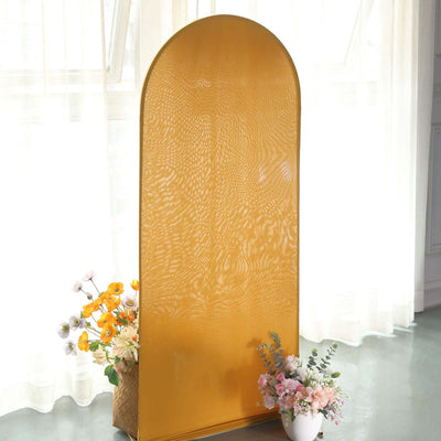 Curved gold mirror with a textured surface and floral arrangement in front.