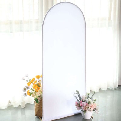 Arch-shaped mirror with floral arrangements in a bright, airy setting.