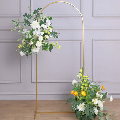 Floral arrangement on a gold arch with greenery and white flowers.