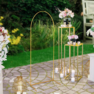 Gold wedding arch with floral arrangements and candle holders in garden setting.