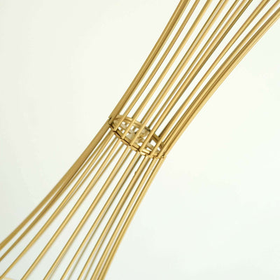 Gold wire sculpture with elegant curves and intricate design detail.