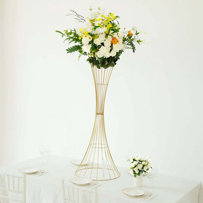 Elegant tall floral arrangement in a modern gold vase on a dining table.