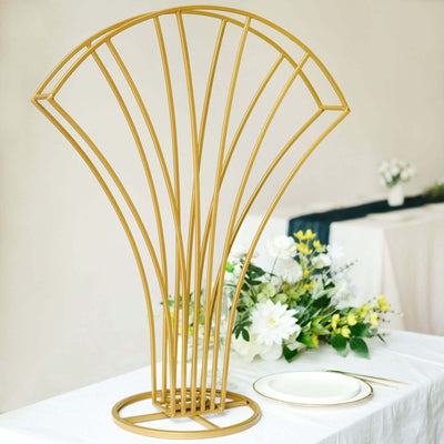 Gold geometric decorative piece on a table with flowers and tableware.