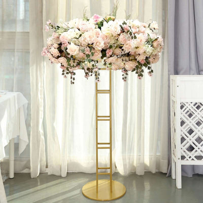Floral centerpiece on a gold stand with pink and white flowers in a bright setting.