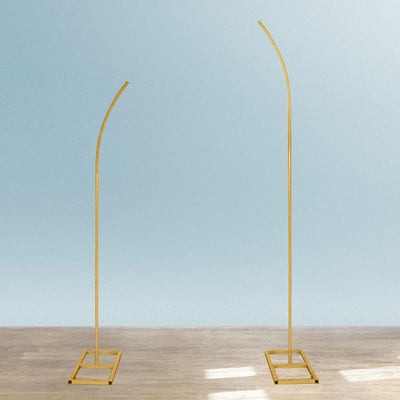 Curved gold display stands on a light wooden floor