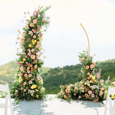 Floral wedding arch with colorful blooms against a scenic backdrop.